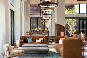 A spacious living area with a sectional sofa, a coffee table, and a dining area with a bar. - Canopy by Hilton Scottsdale Old Town (Scottsdale)