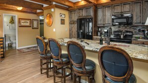 A kitchen with wooden cabinets, a refrigerator, a stove, and a bar area with four chairs. - Platinum Luxury Condo in Heart of Avon A606 (Avon)