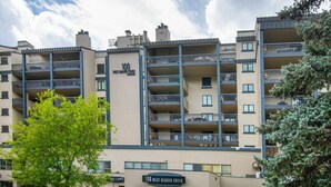 A multi-story building with balconies, a sign indicating '100 West Beaver Creek,' and a parking area with cars. - Platinum Luxury Condo in Heart of Avon A606 (Avon)