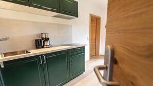 Una cocina con armarios verdes, una cafetera y un lavavajillas.