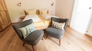 Un dormitorio con cama, dos sillones y un armario de madera.