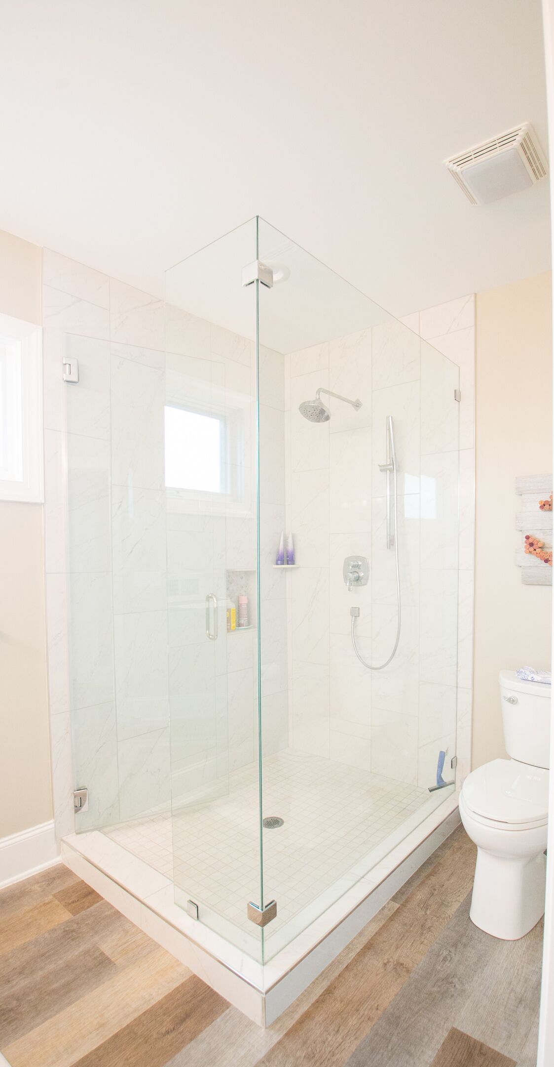 A modern bathroom with a glass-enclosed shower, a toilet, and a sink.