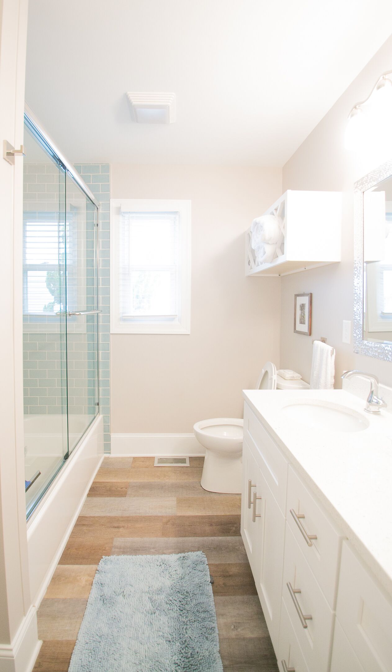 Une salle de bain avec une douche à parois de verre, des toilettes, un lavabo avec un miroir et une fenêtre.