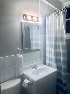 Bathroom features a sink, mirror, toilet, and striped shower curtain.