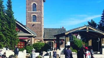 A public square with a prominent brick tower, a covered pavilion, and a red building with a sign.