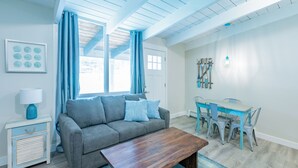 A modern living room with a grey sofa, wooden coffee table, and a dining area with a blue table and chairs. - Mountain View Boutique Suite with contactless entry - The Lake at Blue Mountains (The Blue Mountains)