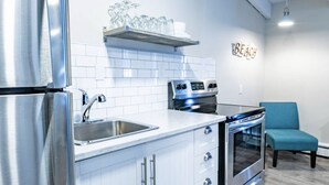 A modern kitchen with stainless steel appliances, white cabinets, and a blue chair. - Mountain View Boutique Suite with contactless entry - The Lake at Blue Mountains (The Blue Mountains)