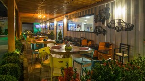Ein Restaurant im Freien mit Tischen und Stühlen, einer Holzbalkendecke und dekorativer Wandgestaltung.