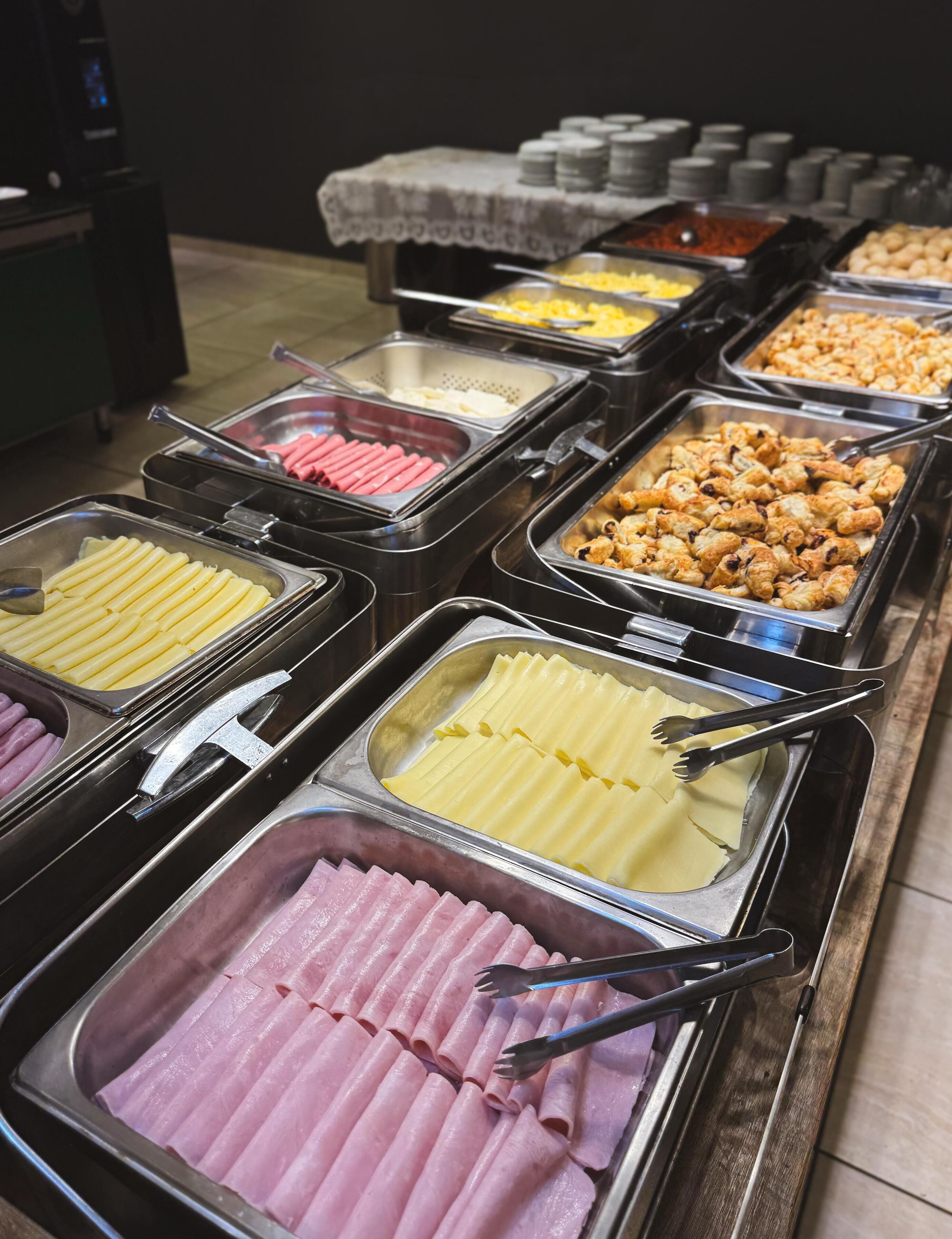 Ein Buffet mit verschiedenen Speisen, darunter Aufschnitt, Käse und Gebäck.