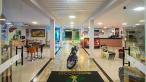 Eine Hotelhalle mit einem Motorrad, einem Empfangsschalter und einer Sitzecke mit Stühlen.