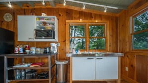 A wooden cabin kitchen with a microwave, sink, and cabinets.