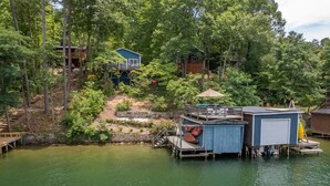 A lakeside cabin complex with multiple buildings, docked boats, and a wooden deck.