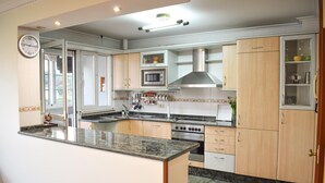 Una cocina moderna con una isla central, electrodomésticos de acero inoxidable y muebles de madera clara.