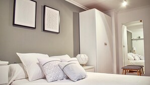 Un dormitorio con cama, dos cuadros enmarcados, un armario y un espejo.