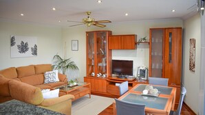 Una sala de estar con sofá, mesa de centro, televisor y armarios de madera.