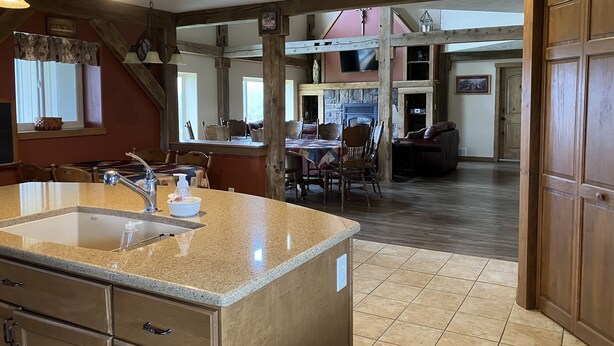 A spacious kitchen with granite countertops, a built-in sink, and wooden cabinetry. There is a dining area with a table and chairs, and a cozy seating area with a couch. - Private Peaceful Country Getaway - Family Friendly - Illinois (Berwick)