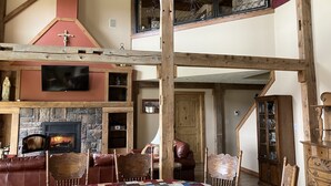 A spacious living area with a fireplace, wooden beams, a TV, and a dining table with chairs. - Private Peaceful Country Getaway - Family Friendly - Illinois (Berwick)