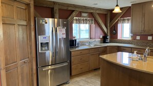 A kitchen with wooden cabinets, a stainless steel refrigerator, a built-in water dispenser, and a large island with a sink. - Private Peaceful Country Getaway - Family Friendly - Illinois (Berwick)
