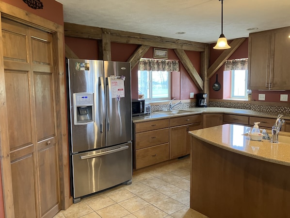 A kitchen with wooden cabinets, a stainless steel refrigerator, a built-in water dispenser, and a large island with a sink.