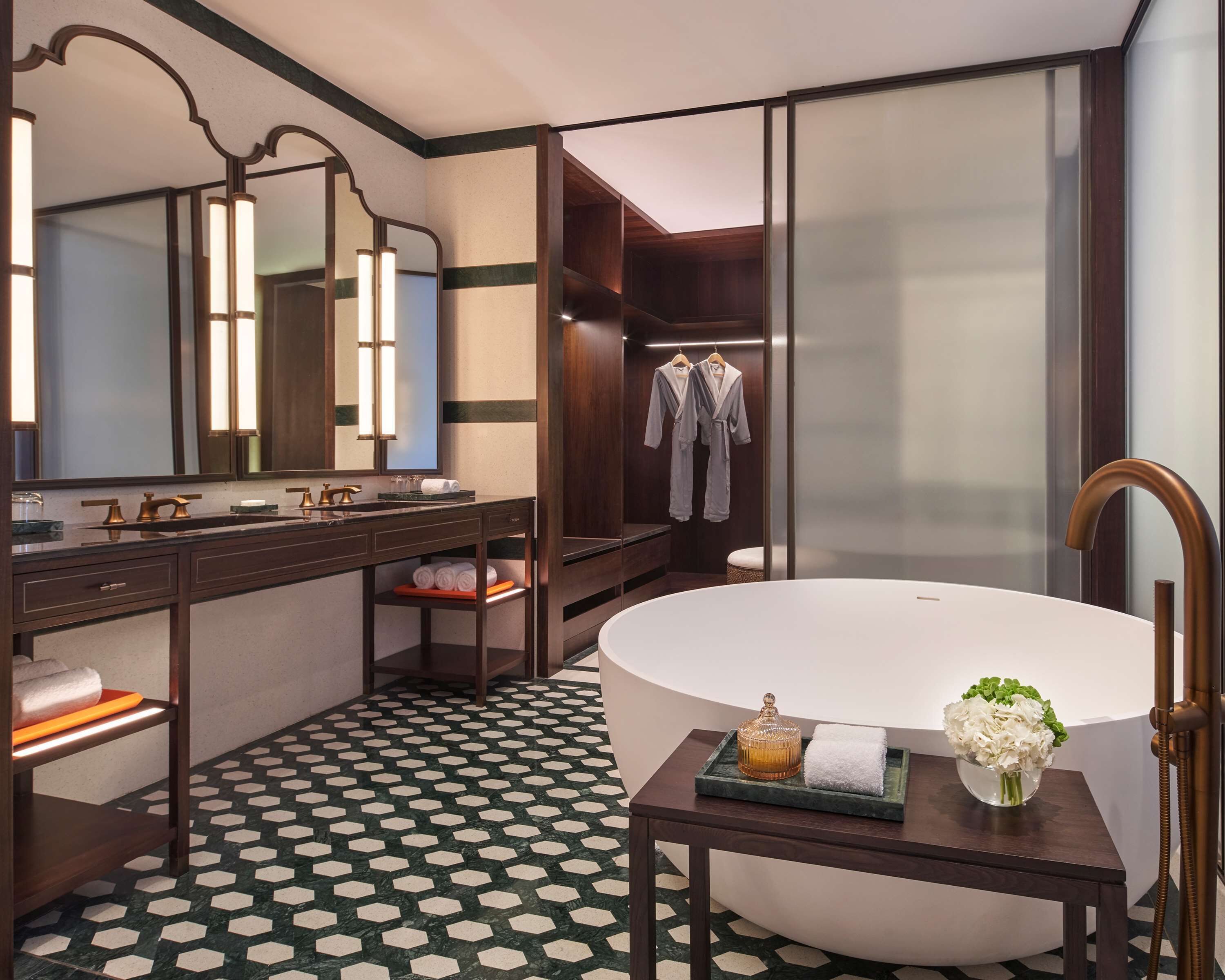 A modern bathroom with a large freestanding bathtub, a vanity with a mirror, and a robe rack.