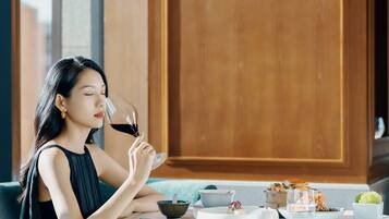 A person seated at a round table with a variety of dishes and a glass of red wine.