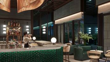 A bar area with a green patterned counter, a bartender, and a shelf of liquor bottles.