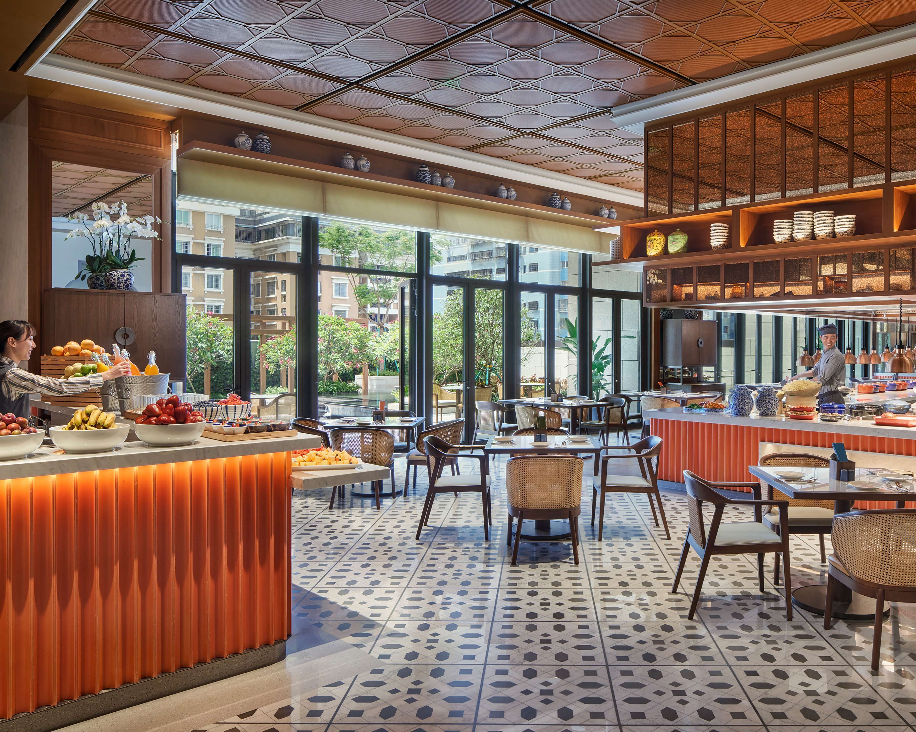 A modern restaurant with a central bar area, dining tables, and chairs.