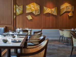 A restaurant interior with wooden panel walls, woven chairs, and tables set for dining. - ANDAZ XIAMEN, BY HYATT (Xiamen)