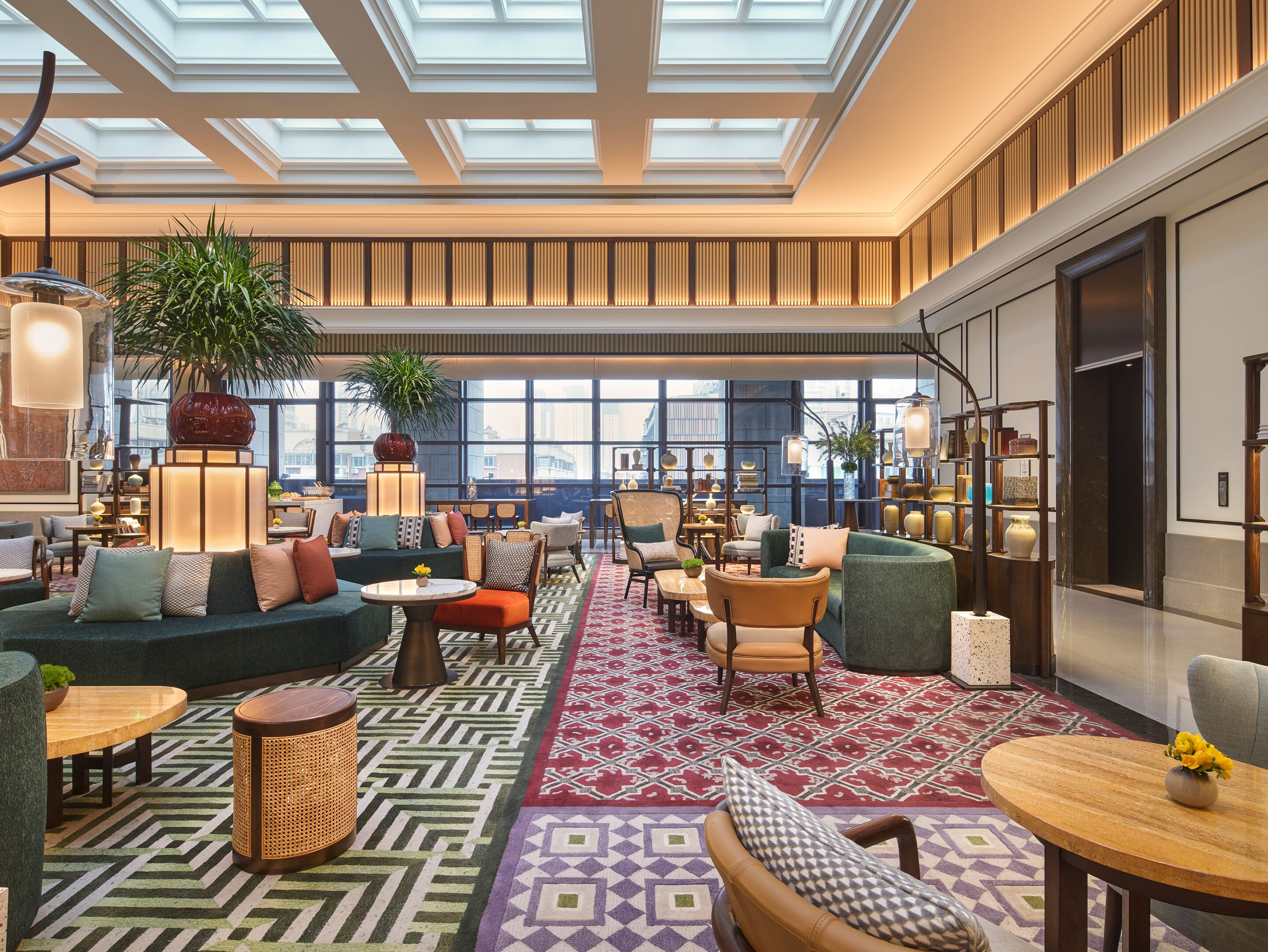 Un hall d’entrée spacieux, doté d’un haut plafond, de grandes fenêtres et de différents types de sièges, notamment des canapés, des fauteuils et des tables.