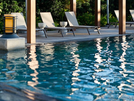 Una piscina al aire libre, sombrillas, sillones reclinables de piscina