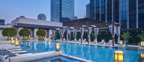 Una piscina al aire libre, sombrillas, sillones reclinables de piscina