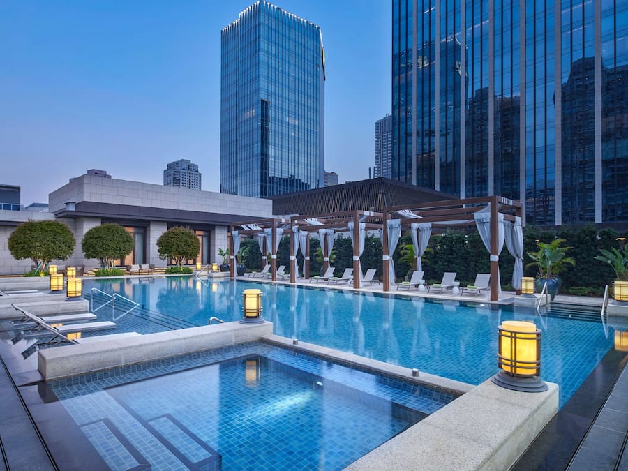 Una piscina al aire libre, sombrillas, sillones reclinables de piscina