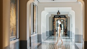 A spacious hallway with a reflective floor, a woman walking, and a large abstract painting on the wall. - ANDAZ XIAMEN, BY HYATT (Xiamen)