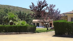 Guests can enjoy a tranquil outdoor seating area surrounded by lush gardens and a scenic hillside backdrop.
