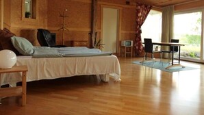 Ein Schlafzimmer mit einem Bett, einem Tisch, einem Stuhl, einem Fernseher und einem Fenster mit Vorhängen.