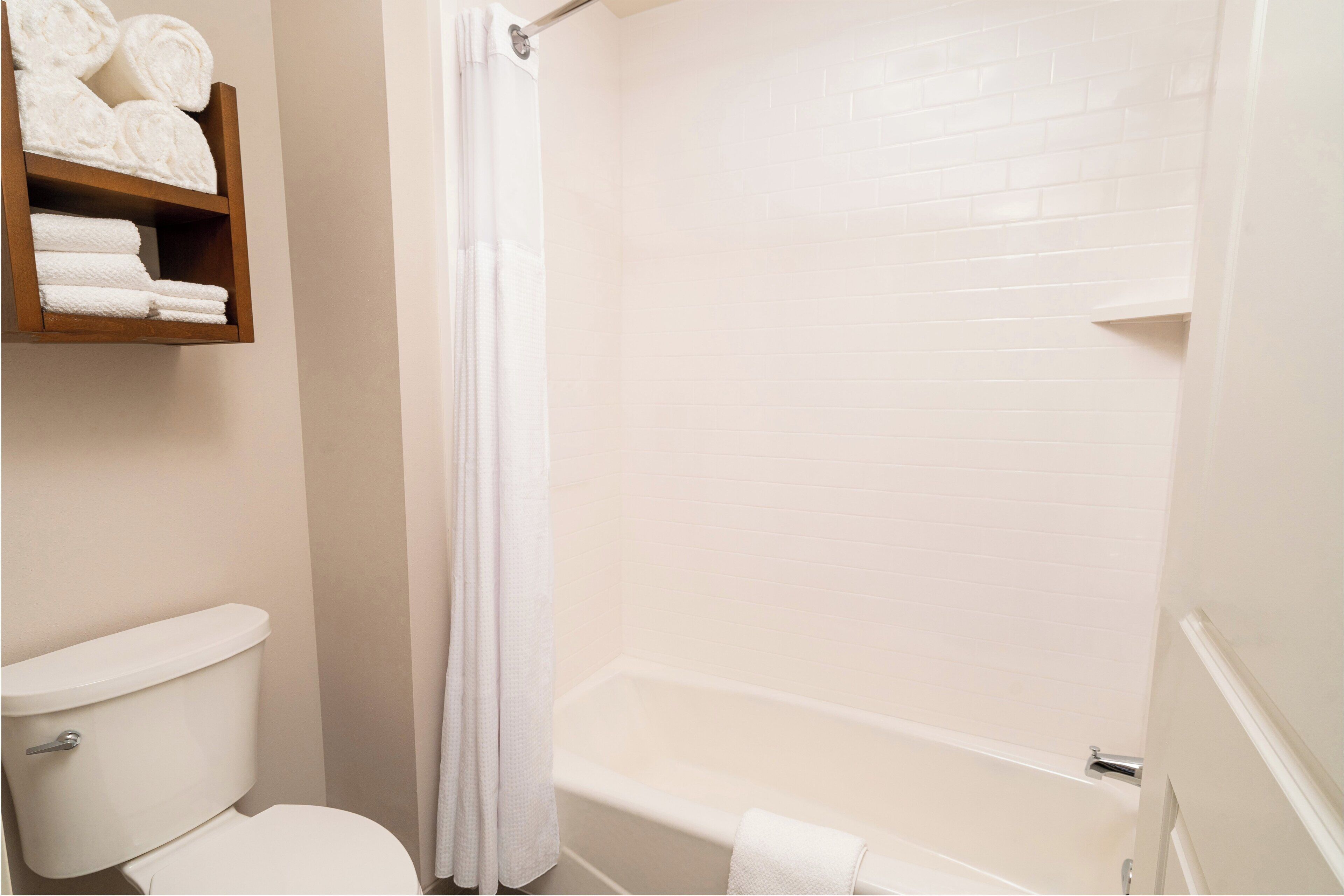 A bathroom with a toilet, a bathtub, and a towel rack with towels.
