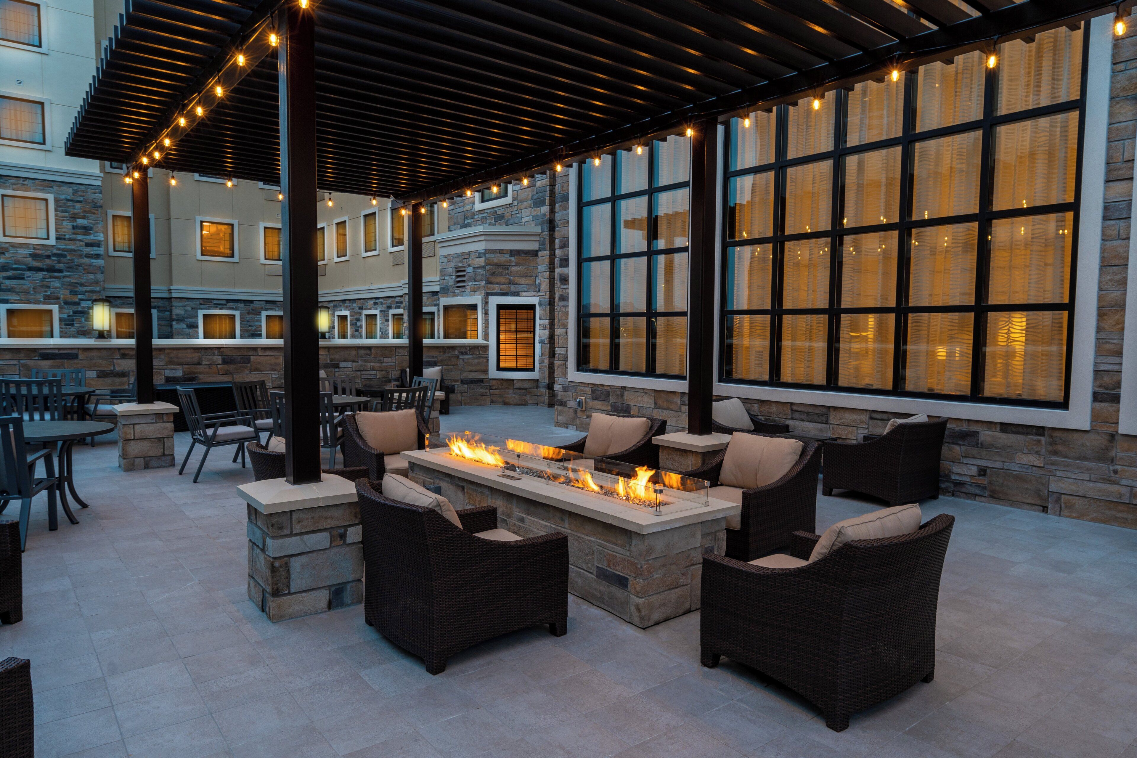 Un espace extérieur aménagé en terrasse, avec des murs en pierre, de grandes fenêtres et un foyer.