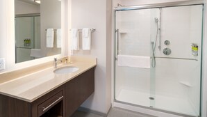 Een moderne badkamer met een douche met glazen wand, twee wastafels en een grote spiegel.
