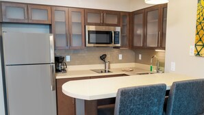 Une cuisine moderne dotée d’appareils électroménagers en acier inoxydable, de meubles en bois et d’un îlot central avec des tabourets de bar.