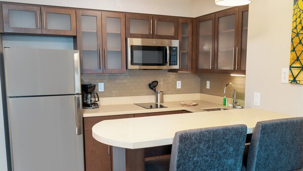 Een moderne keuken met roestvrijstalen apparatuur, houten kasten en een centraal eiland met barstoelen.