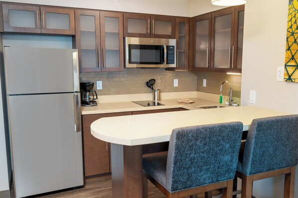 Una cocina moderna con electrodomésticos de acero inoxidable, armarios de madera y una isla central con taburetes de bar.