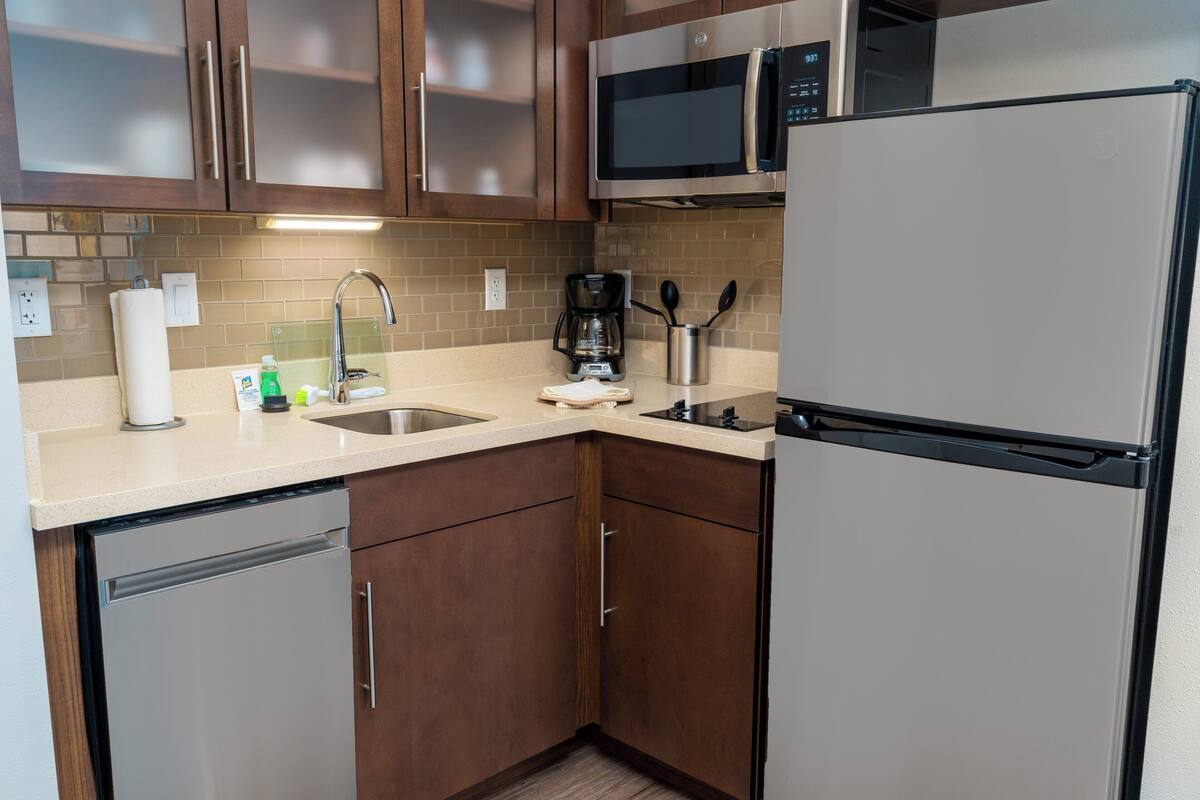 Una cocina compacta equipada con lavavajillas, microondas, refrigerador, cafetera y lavabo.
