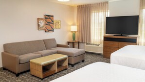 Een hotelkamer met een bank, een tafeltje, een televisie, een bed en een lamp.