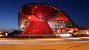 En moderne bygning med et markant rødt tag og glasfacade, der viser BMW Welt logoet.
