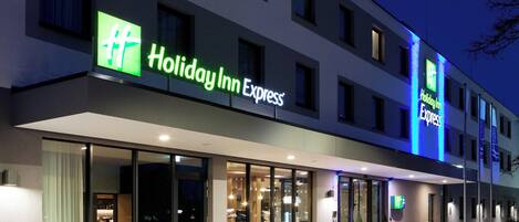 A Holiday Inn Express hotel with a modern facade, large glass windows, and a well-lit entrance.