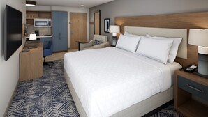 A hotel room with a large bed, a desk, a chair, a TV, a microwave, and a kitchenette. - Candlewood Suites Odessa Midland by IHG (Odessa)