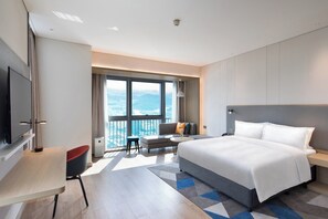 Una moderna camera d'albergo con un letto grande, una scrivania, una sedia e vista sulla città.