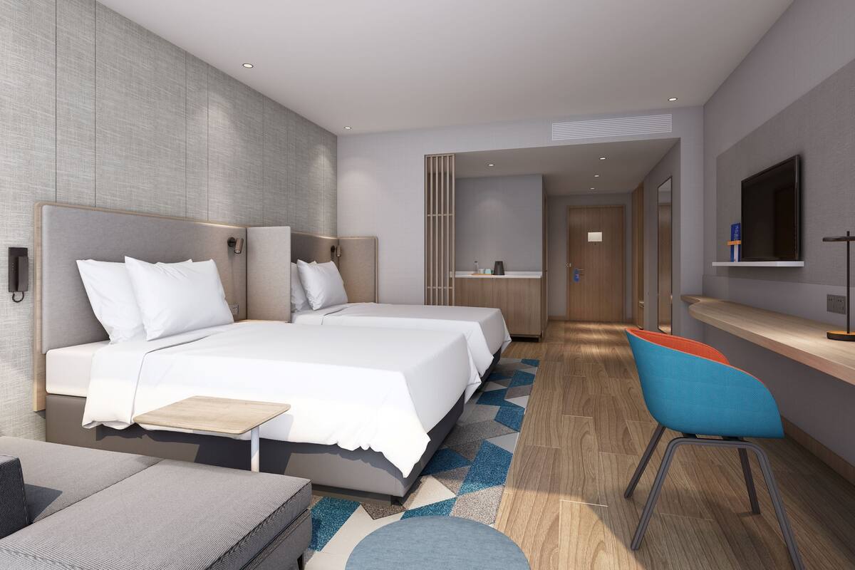 Een moderne hotelkamer met een groot bed, een bureau en een stoel.