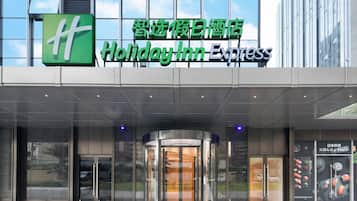 La entrada a un hotel Holiday Inn Express, con fachada de vidrio y puerta giratoria.