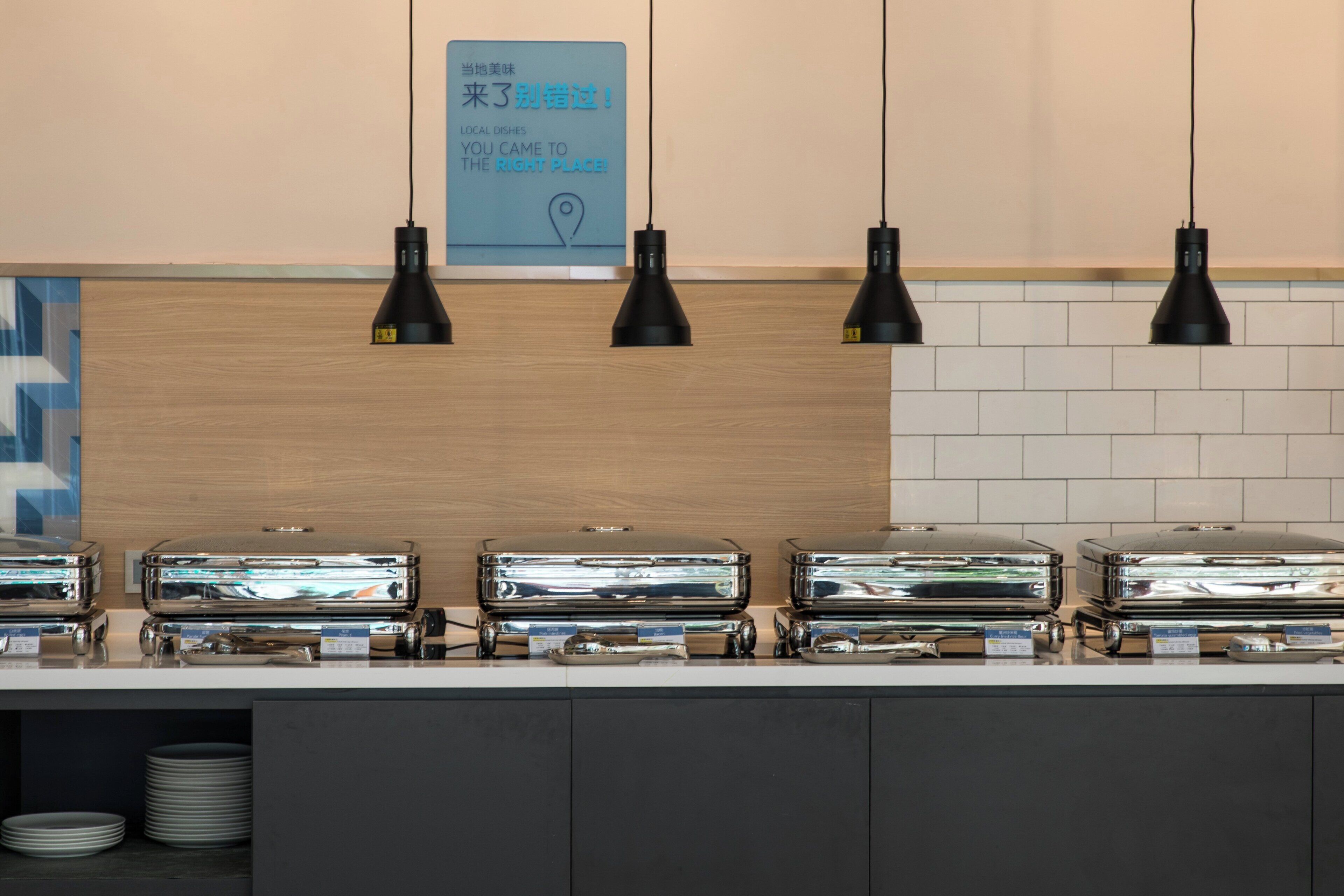 Un buffet avec plusieurs présentoirs à aliments et un éclairage installé au-dessus.